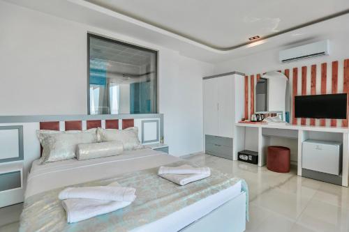 a white bedroom with a large bed and a tv at Stonehillkaş in Kas