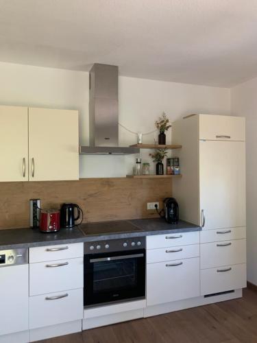 a kitchen with white cabinets and a black appliance at Ferienwohnung KaRo in Bodensdorf