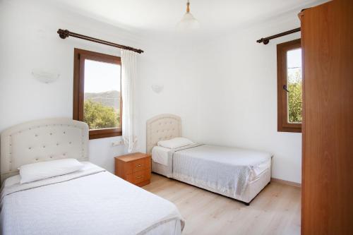 two beds in a white room with two windows at Flat w Nature View Balcony 1 min to Beach in Datca in Datca