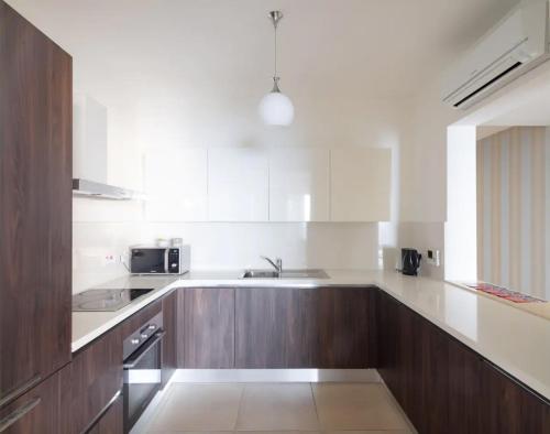 a kitchen with wooden cabinets and a sink at Seafront Apartment Sliema in Sliema