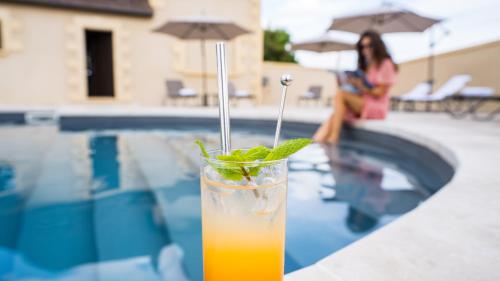 a drink sitting on a table next to a swimming pool at Hotel Le Perigord in La Roque-Gageac