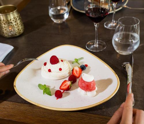 a plate of food with strawberries and whipped cream at Hotel Le Perigord in La Roque-Gageac