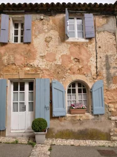 an old building with blue shuttered windows and flowers at La maison de Muriel in Rustrel