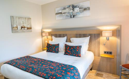 a bedroom with a large bed with red and blue pillows at Hotel Le Perigord in La Roque-Gageac