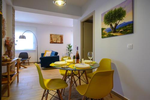 a living room with a table and yellow chairs at Chic Apartment in Nature in Kalamata
