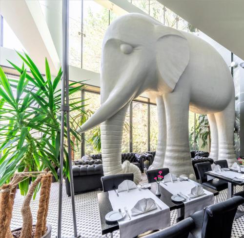 a large elephant statue in a restaurant with tables at Rixwell Elefant Hotel in Rīga