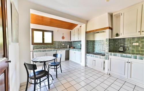 una cucina con armadi bianchi, tavolo e sedie di 3 Bedroom Awesome Home In Saint-pierre-de-vassol a Saint-Pierre-de-Vassols