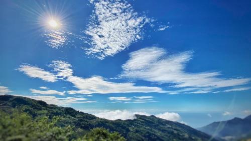 a blue sky with the sun and clouds over mountains at Mountain Lodge in Taimali