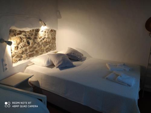a bedroom with a bed with white sheets and pillows at Aiolos TRADITIONAL HOUSE IN ASTYPALAIA in Astypalaia