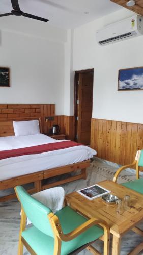 a room with a bed and a table and chairs at Hotel CM Palace - Pure Vegetarian in Ner Chowk