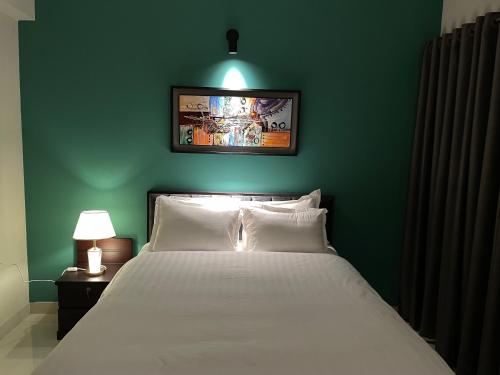 a bedroom with a white bed and a green wall at CityLights - Mayfair Signature Collection Gulshan in Dhaka