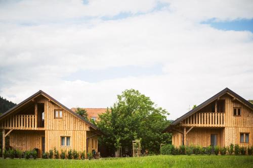 two wooden houses in a field with trees at Family Bungalow Glamping Laško in Laško