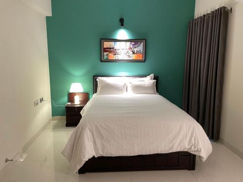 a bedroom with a large bed with a blue wall at CityLights - Mayfair Signature Collection Gulshan in Dhaka