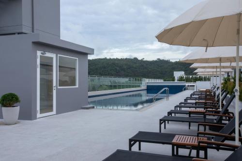 a patio with tables and umbrellas and a swimming pool at Kantary Hotel Banchang in Ban Chang