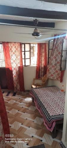 バラナシにあるKALYANI HOME STAY IN VARANASIの赤いカーテン付きのベッドルーム1室、ベッド1台が備わるベッドルーム1室が備わります。