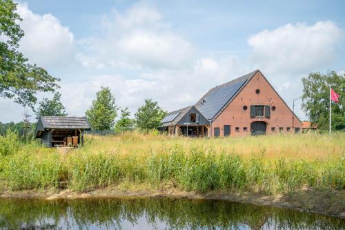 a barn and a house in a field next to a river at Het Heerengoedt in Ambt Delden