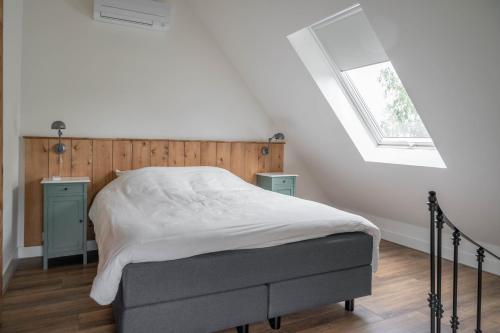 a bedroom with a bed with a wooden headboard and a window at Het Heerengoedt in Ambt Delden