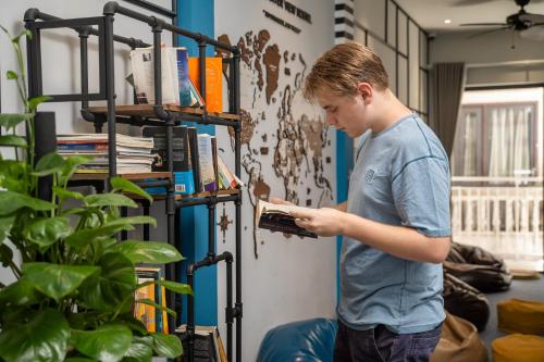 a young man standing in a room holding a book at Old Quarter View Hanoi Hostel in Hanoi