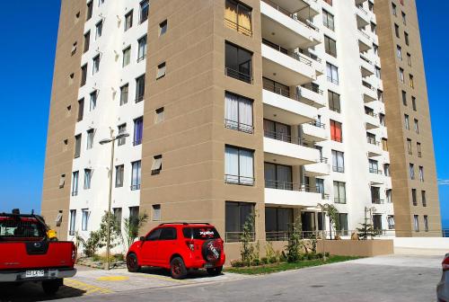 a red car parked in front of a tall building at Apartamento El Yodo in Antofagasta
