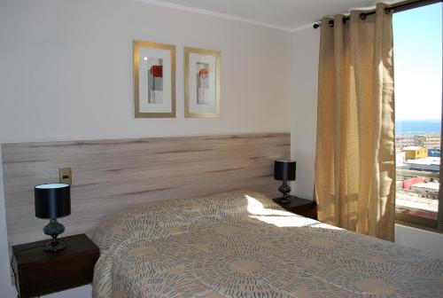 a bedroom with a bed with two lamps and a window at Apartamento El Yodo in Antofagasta