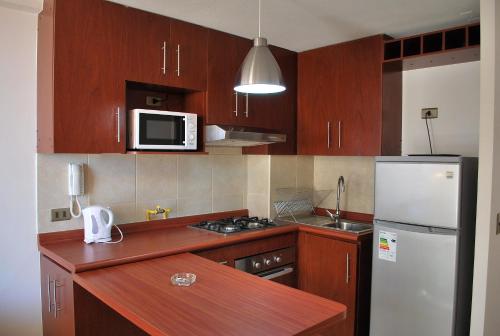 cocina con armarios de madera y nevera blanca en Apartamento El Yodo, en Antofagasta