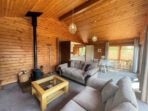 a living room with two couches and a table with a fireplace at Pass the Keys Beautiful 2BR Beach Lodge Set In Stunning Gardens in Dalbeattie