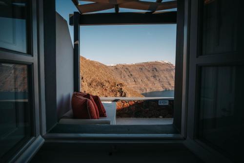 a window with a view of a mountain view at San Antonio - Small Luxury Hotels of the World in Imerovigli