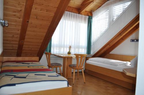 a room with two beds and a table and a window at Pension Keller in Reichenau