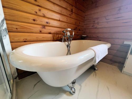 a white bath tub in a bathroom with wooden walls at Pass the Keys Beautiful 2BR Beach Lodge Set In Stunning Gardens in Dalbeattie