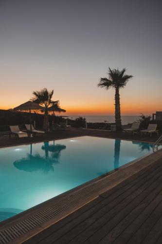 a swimming pool with palm trees and a sunset at Argo-Milos in Adamas
