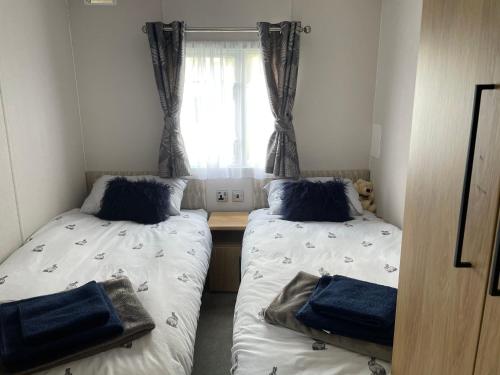 two beds in a small room with a window at Summer’s Lodge in Swarland