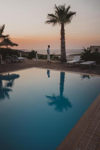 a man walking by a swimming pool with a palm tree at Argo-Milos in Adamas