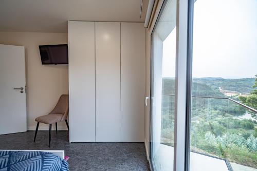 a room with a large glass window and a chair at Casa da Bina in Paredes