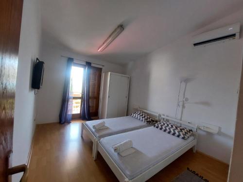 a white bedroom with a bed and a television at Studio-app Iva, balcony with sea view - 50 m from beach in Pag