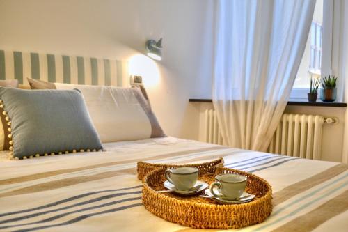 a tray with cups and saucers on a bed at Casa dell'Arco - 1 min walking from the beach in Santa Margherita Ligure