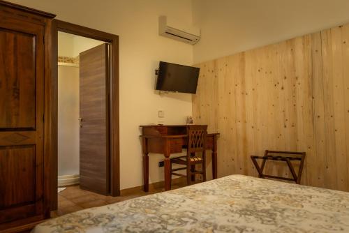 a bedroom with a bed and a desk and a television at L'Antico Vigneto in Marino