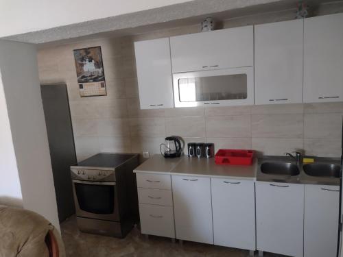 eine Küche mit weißen Schränken, einer Spüle und einem Herd in der Unterkunft Apartments Pekic in Vranjina