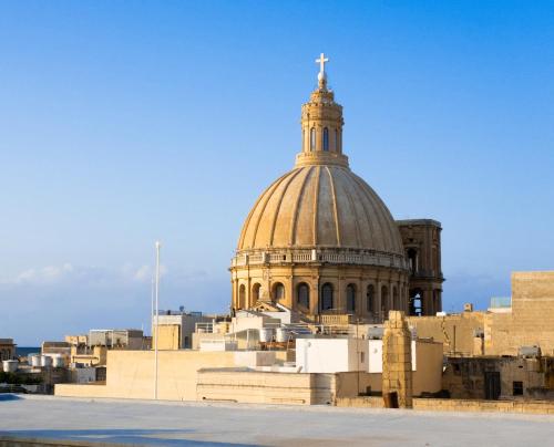 Un edificio con una cupola con una croce sopra. di Mulberry Suites a La Valletta