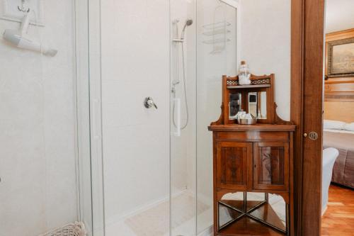 a shower with a glass door next to a wooden cabinet at Villa Luigi XVI in Taranto
