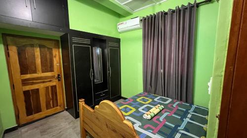 a green room with a bed and a door at Ramya’s Villa in Trincomalee