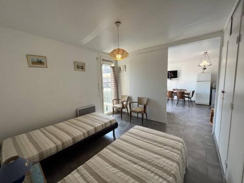 une chambre avec deux lits et une salle à manger dans l'établissement Appartement rénové T3, 6 couchages, proche plage et commerces, parking sécurisé, animaux acceptés - FR-1-106-56, à Saint-Cyprien