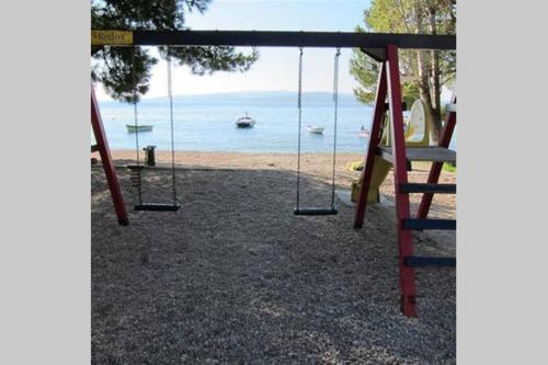 a playground with a swing and a beach at Vila Anda in Promajna