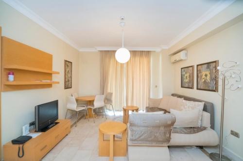 ALANYA GOLD CİTY في ألانيا: غرفة معيشة مع أريكة وتلفزيون وطاولة