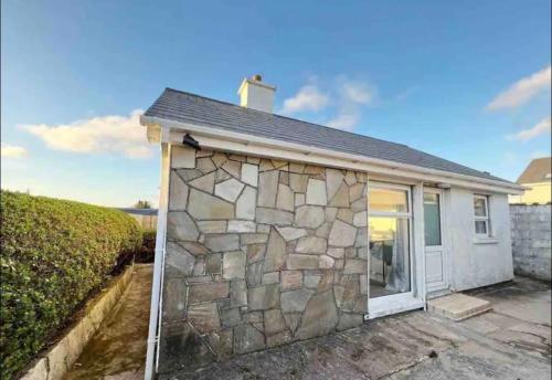 a small stone house with a stone wall at The Chalet in Dungloe