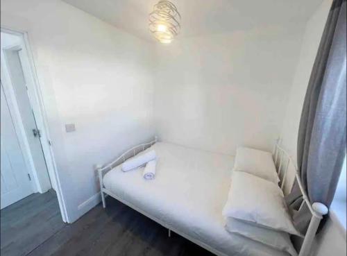 Cama blanca en habitación con luz en la pared en The Chalet, en Dungloe