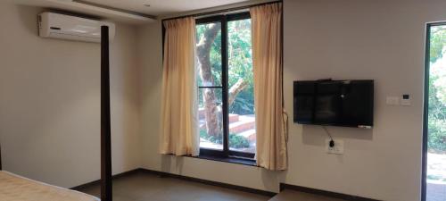 a bedroom with a large window with a television at R R Heritage Resort Pure Vegetarian in Mahabaleshwar