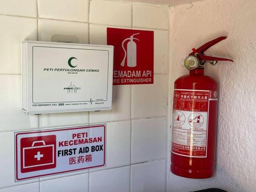 a red fire extinguisher on a wall with signs at Cozy Stay At Raintown Taiping in Kamunting