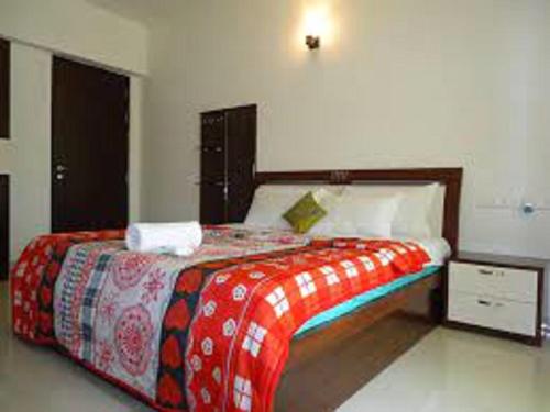 a bedroom with a bed with a red and white blanket at Oragadam Rooms By Actisai in Oragadam