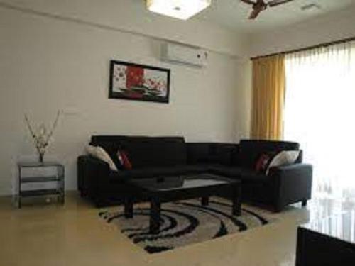 a living room with a black couch and a coffee table at Oragadam Rooms By Actisai in Oragadam