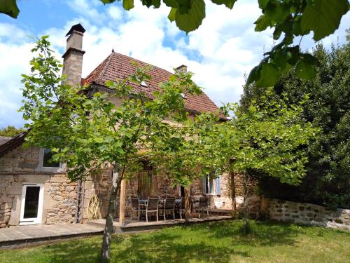 an external view of a stone house with a table and chairs at Maison Village Hautefage in Hautefage